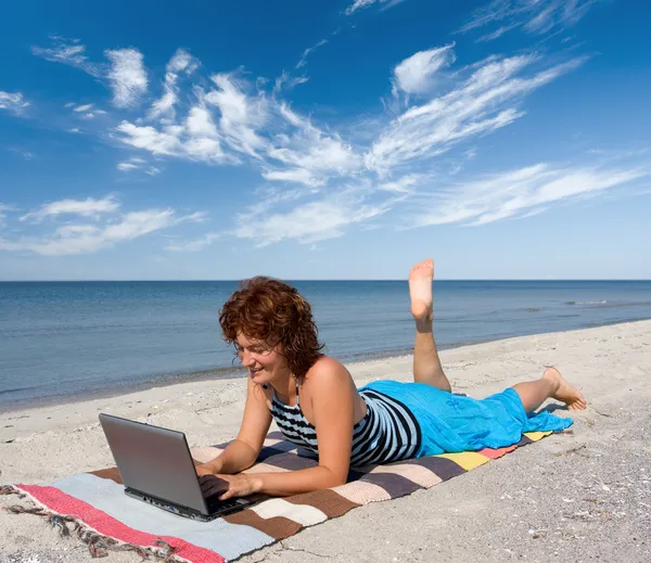 Ragazza con computer portatile sulla riva del mare — Foto Stock