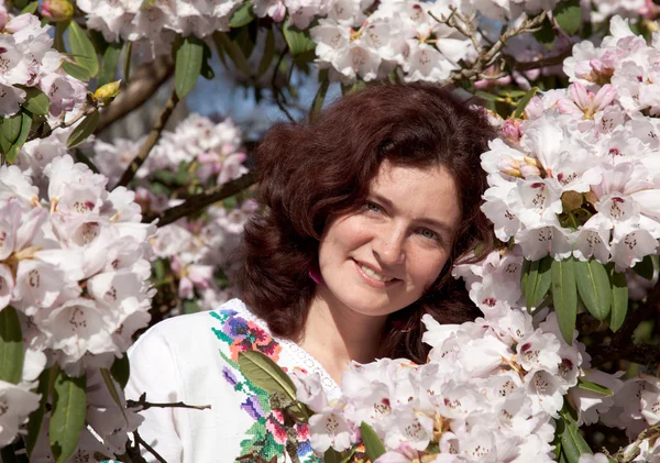 Smiling girl in flowering bush — Stock Photo, Image