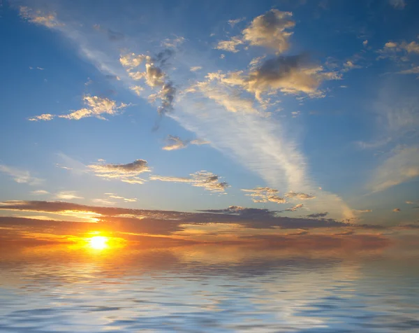 Salida del sol sobre el agua y el cielo con nubes — Foto de Stock