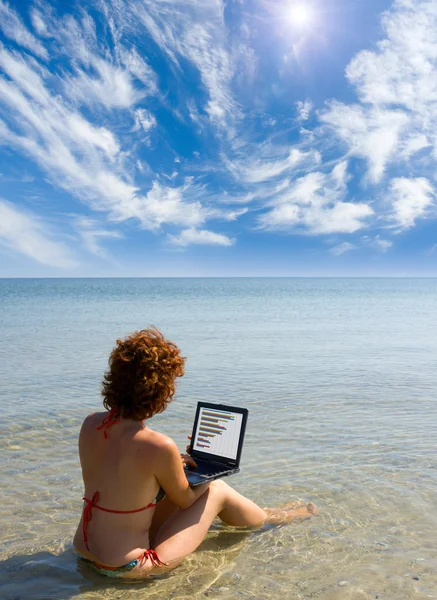 Girl with laptop sitting in the sea — Stock Photo, Image