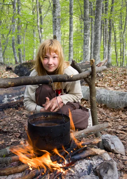 Mädchen sitzt am Lagerfeuer im Wald — Stockfoto