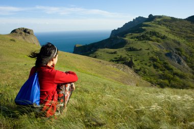 Woman sitting on a hill over sea clipart