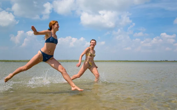 Girls running and jumping above water — Stock Photo, Image