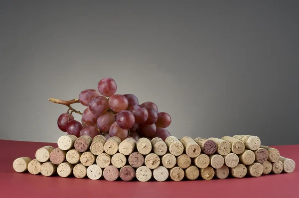 Red grape and group of wine corks — Stock Photo, Image