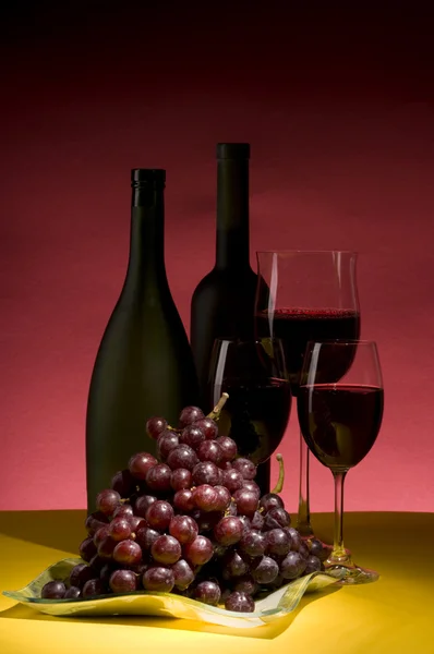 Red grape and wine bottle still life — Stock Photo, Image
