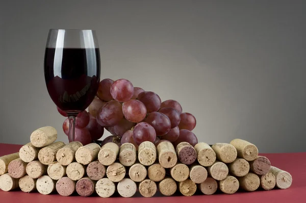 Red wine glass with grape and corks. — Zdjęcie stockowe