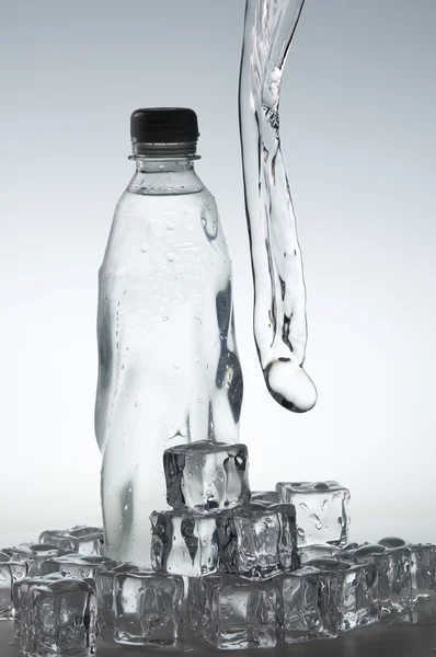 Ice cubes and mineral water bottle — Stock Photo, Image