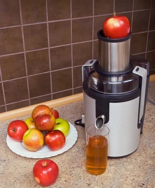 Juicer, äpplen, ett glas saft — Stockfoto