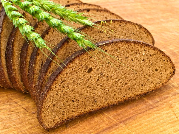 Brood en graan op houten plank — Stockfoto
