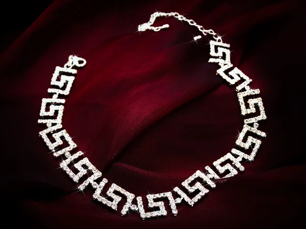Серьги из ожерелья на красной ткани — стоковое фото