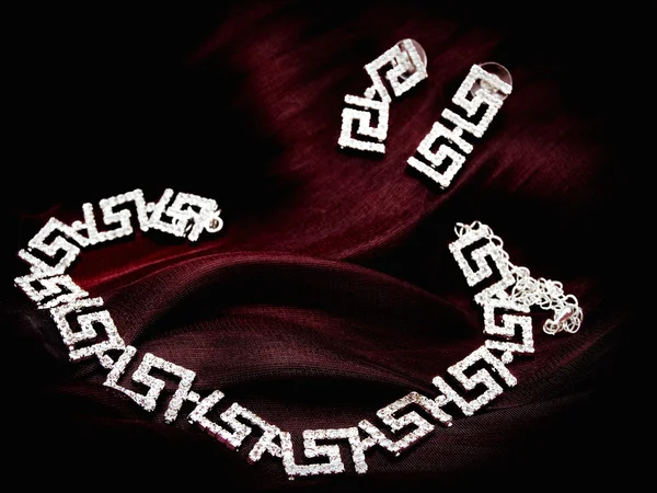 Серьги из ожерелья на красной ткани — стоковое фото