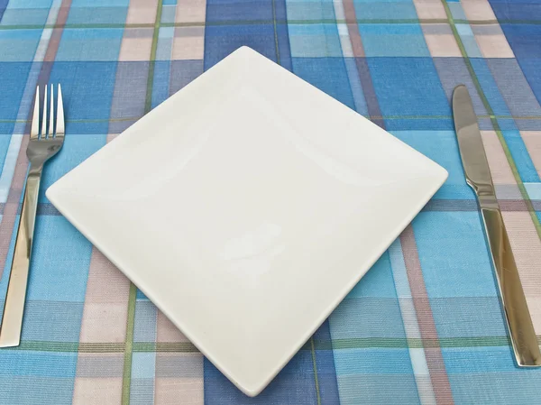 Prato com garfo e faca na toalha de mesa — Fotografia de Stock