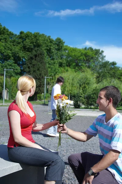 Guy gives to girl flowers — Stock Photo, Image