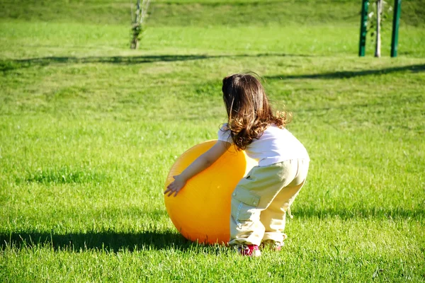 Маленька дівчинка грає з жовтим м'ячем — стокове фото