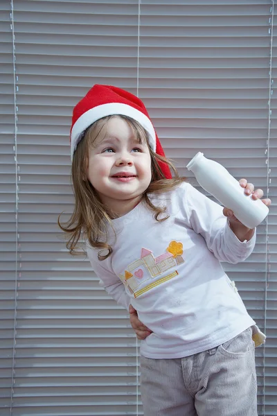 Girl with bottle and in Santa Claus hat — Stock Photo, Image