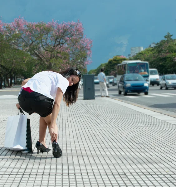 Женщина регулирует свою обувь на тротуаре — стоковое фото