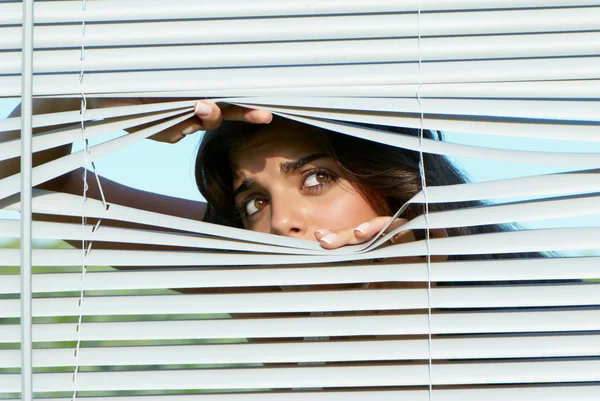 Chica mirando a través de las persianas —  Fotos de Stock