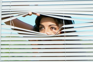 Girl looking through the blinds clipart