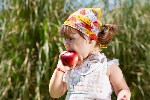 Little girl eats peach — Stock Photo, Image