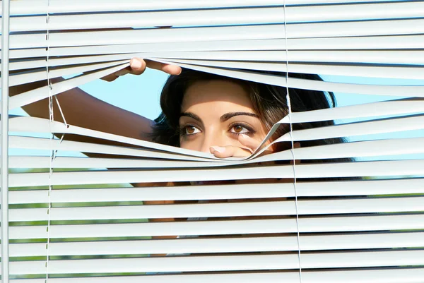Chica mirando a través de las persianas — Foto de Stock
