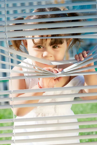Bambina che guarda attraverso le tende — Foto Stock