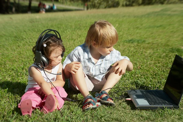 Menino e uma menina com laptop no parque — Fotografia de Stock