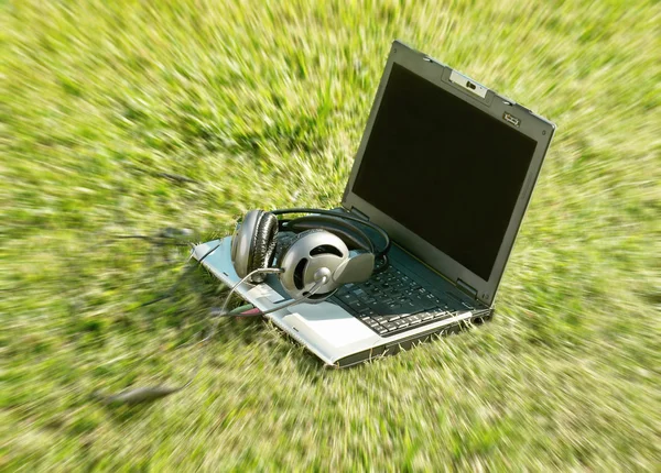 Laptop e fones de ouvido em um parque — Fotografia de Stock
