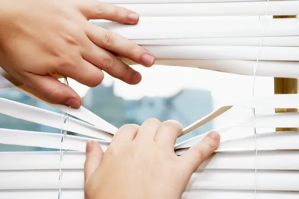 Hands apart on the window blinds — Stock Photo, Image