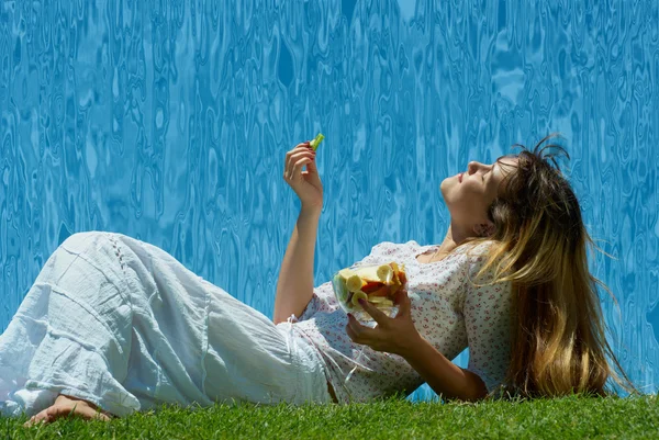 Meisje eet vruchten op het gras — Stockfoto