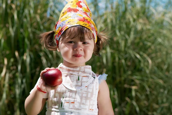 Klein meisje eet perzik in het park — Stockfoto