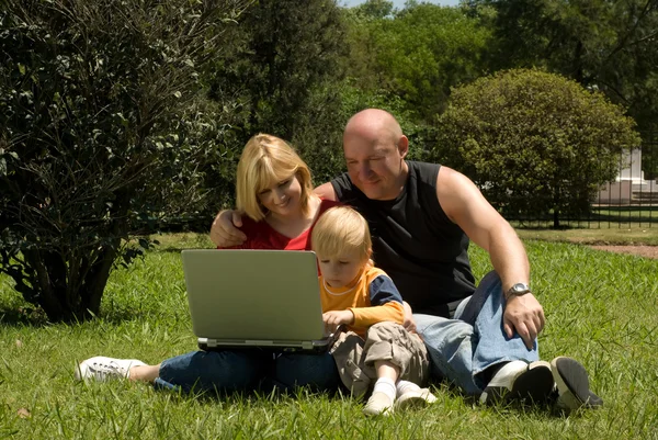 Мати батько і син в парку вивчають ноутбук — стокове фото
