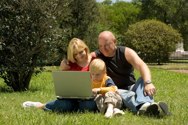 Matka otec a syn v parku studují notebook — Stock fotografie