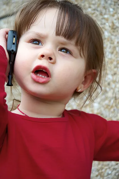 Klein meisje praten op een mobiele telefoon — Stockfoto