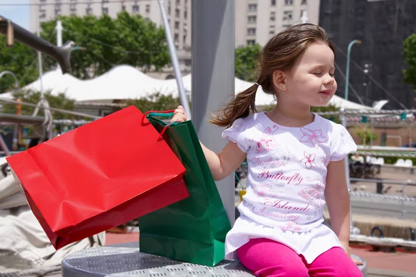 Dítě sedí s nákupní tašky a vítr se těší — Stock fotografie
