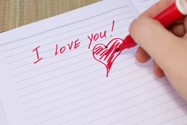 Pessoa escreve e desenha um coração com um lápis vermelho — Fotografia de Stock