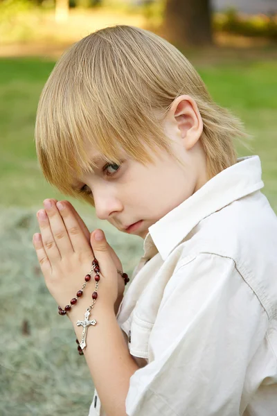 Маленький мальчик молится цепью — стоковое фото