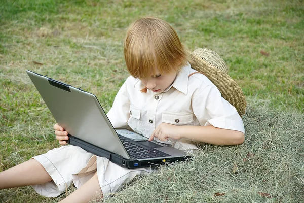 Garçon travaille sur un ordinateur portable alors qu'il est assis dans un parc — Photo