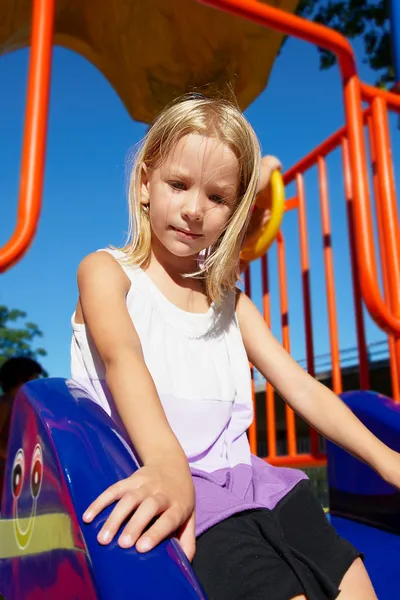 Menina montando em um balanço no playground — Fotografia de Stock