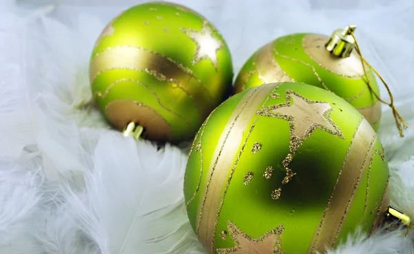 Green christmas bubbles on white feather — Stock Photo, Image