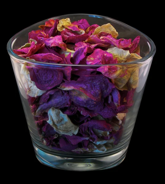 Bloemblaadjes van een roos in een glas. — Stockfoto