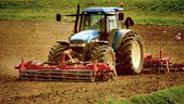 Grunge-Bild eines Traktors auf Ackerland