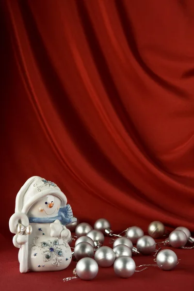 Sneeuwpop op rode satijnen achtergrond — Stockfoto