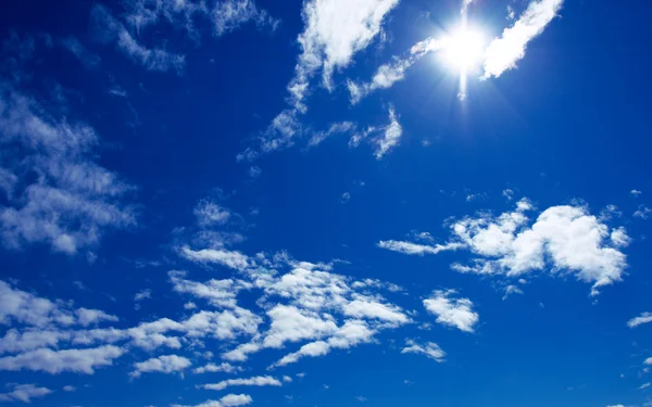 Zon en wolken op blauwe hemel — Stockfoto