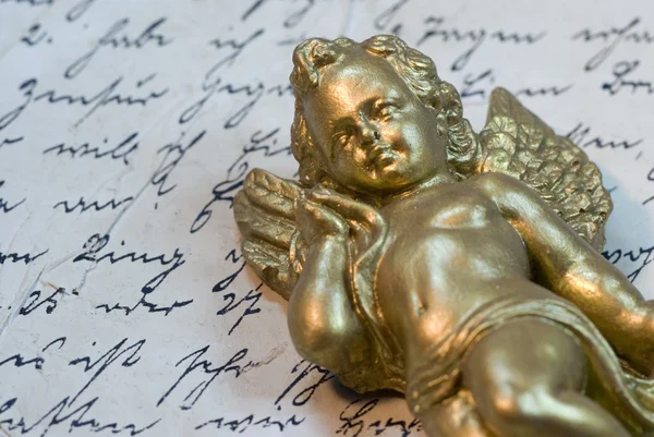 Little angel statue on old letter — Stock Photo, Image