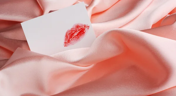 Opmerking op beige zijde. een afdruk van lippenstift — Stockfoto