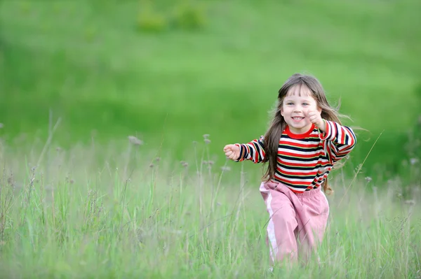 A garota correndo em um campo verde — Fotografia de Stock