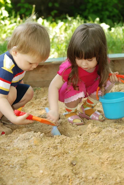 De jongen en meisje spelen aan een sandbox — Stockfoto