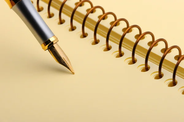 Перьевая ручка на желтой записной книжке — стоковое фото