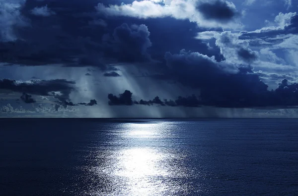 Regn och solsken över havet Stockbild