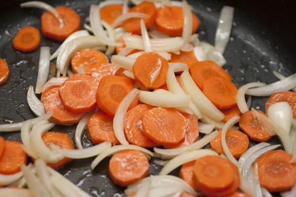 Καρότα και τα κρεμμύδια σε ένα τηγάνι Εικόνα Αρχείου